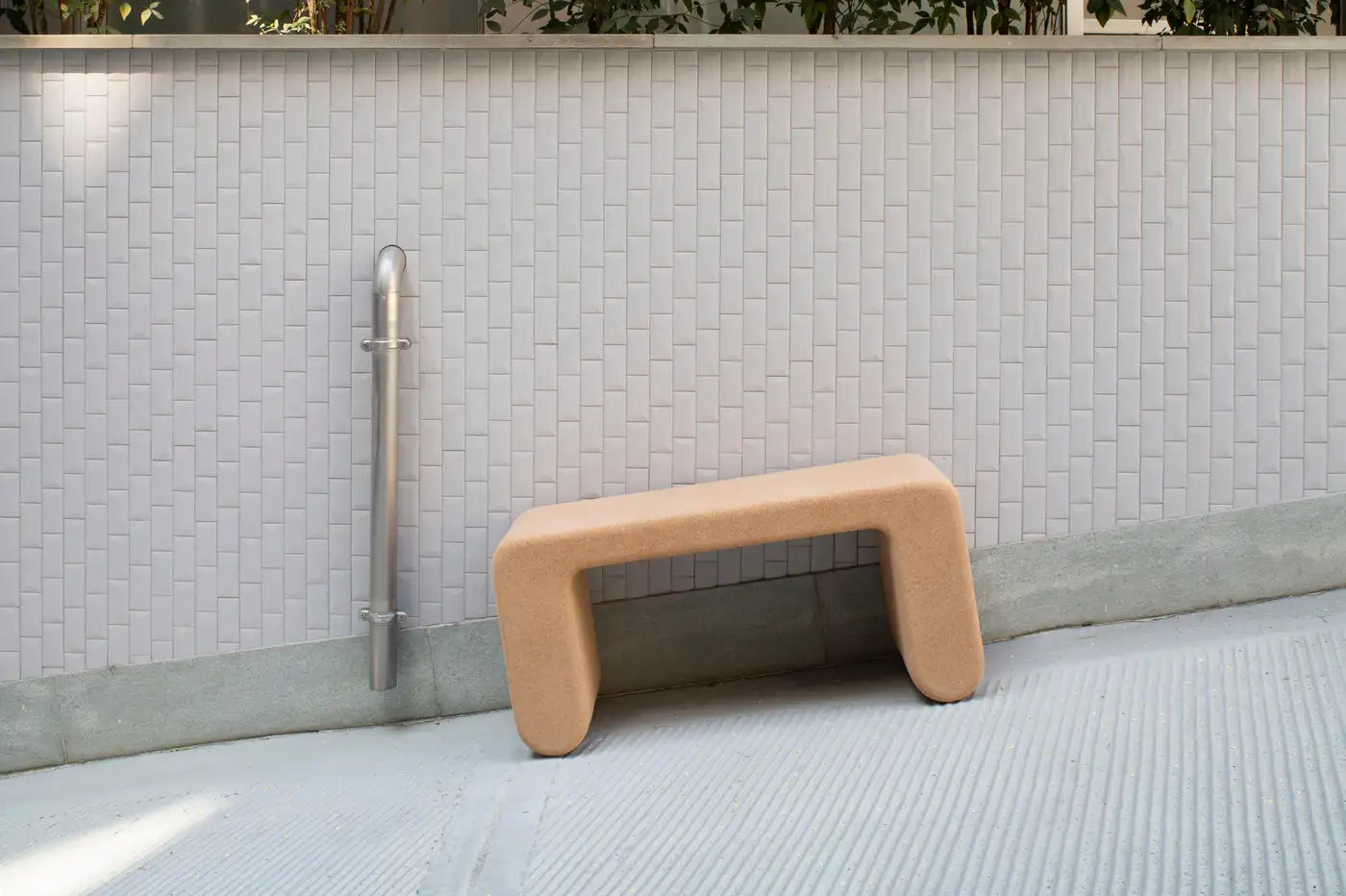 Modern outdoor bench against a tiled wall with a light gray floor.