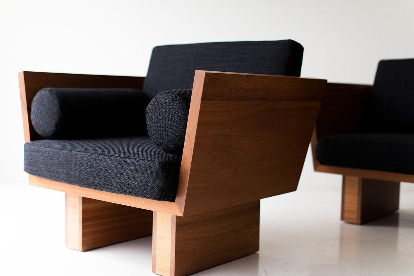 Modern chair with wooden frame and dark cushions on a white background