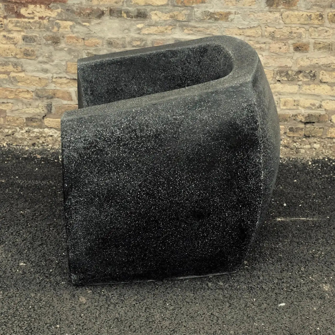 Black stone planter against a brick wall