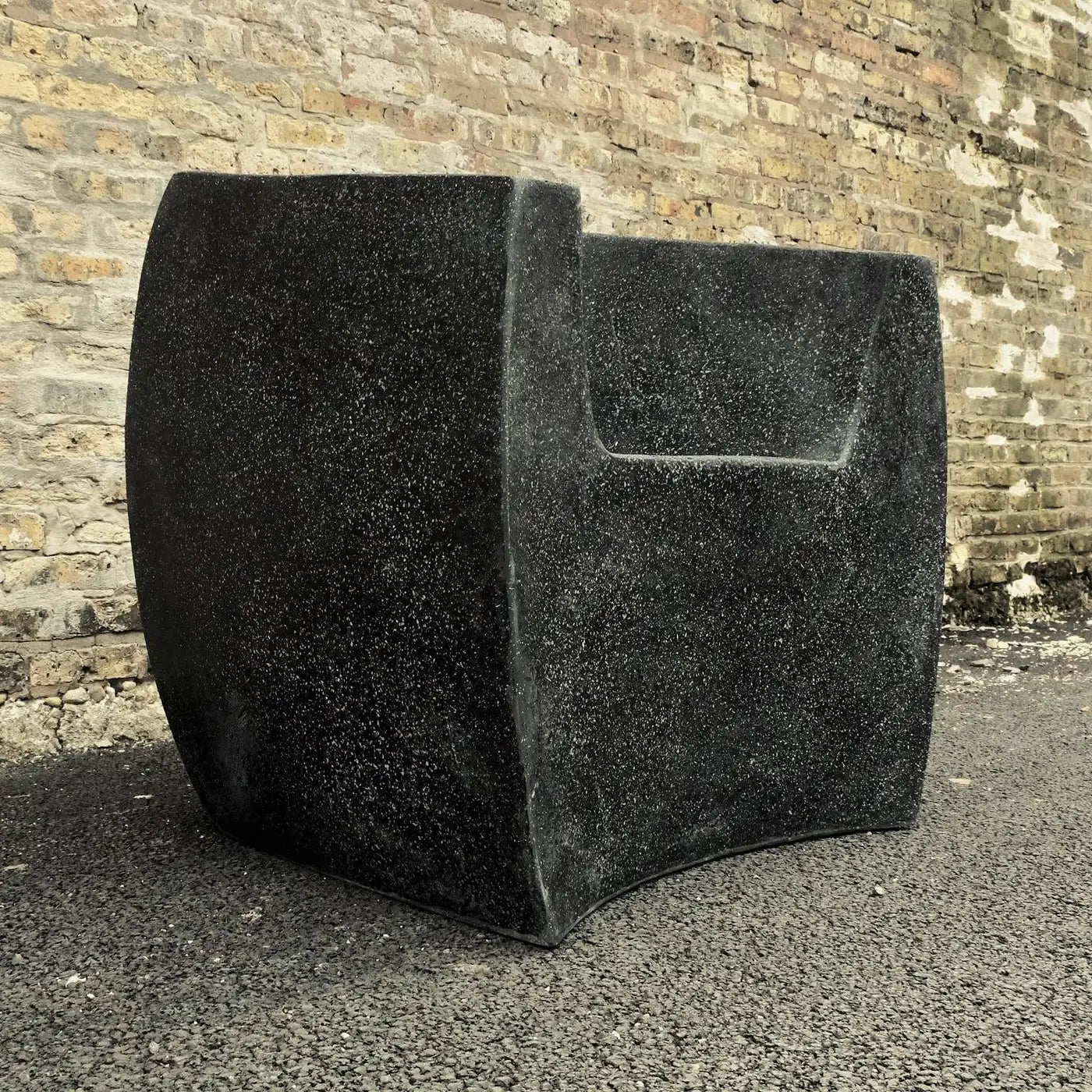 Black speaker enclosure against a brick wall
