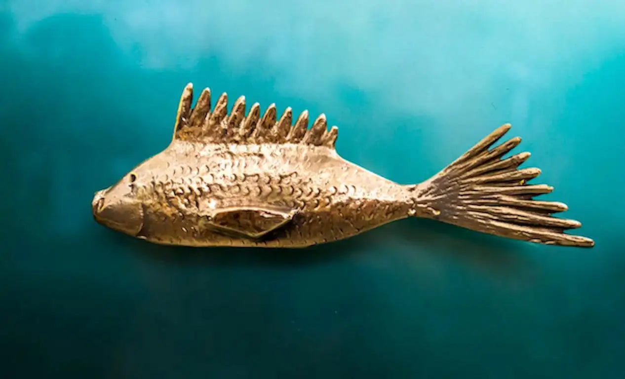 Bronze fish sculpture on a teal background
