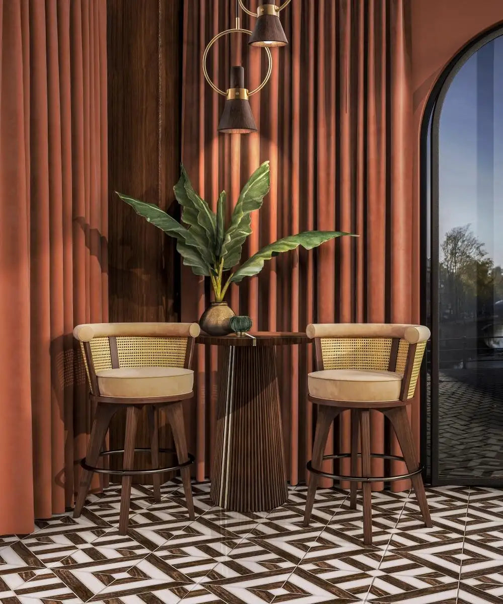 Two bar stools with a small table and plant against a red curtain.