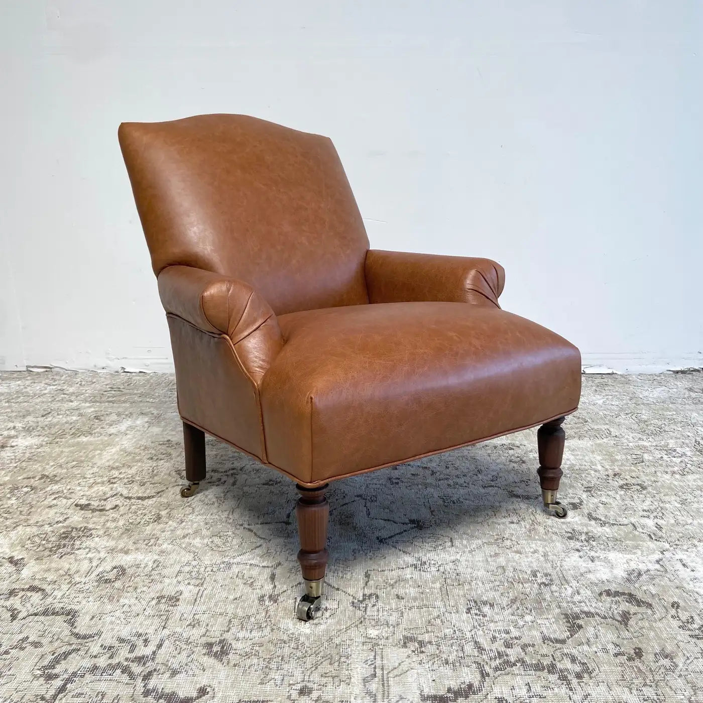 Brown leather armchair on a textured floor with a white wall background