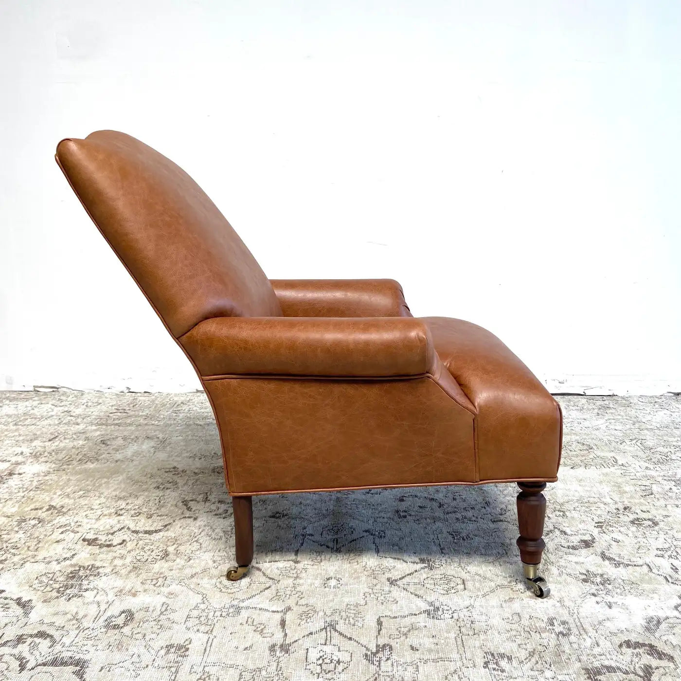 Brown leather armchair on a textured rug with a white background