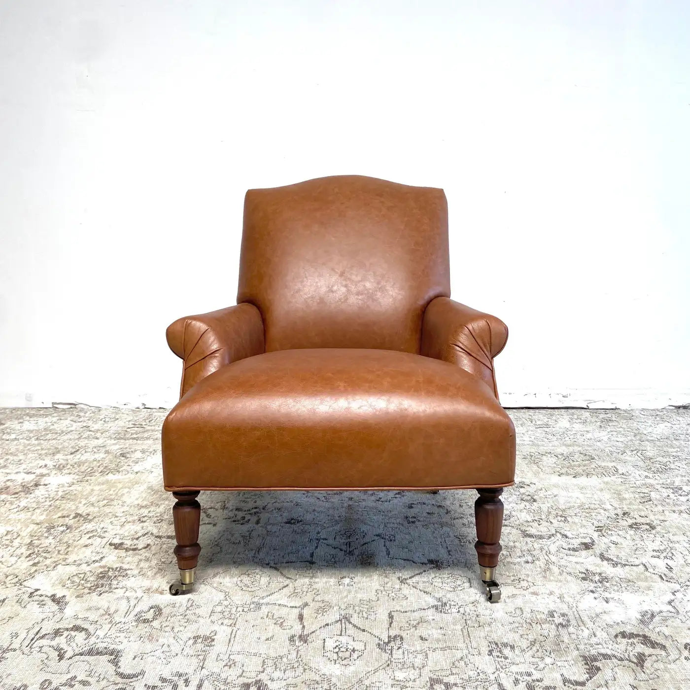 Brown leather armchair on a textured floor with a white wall background