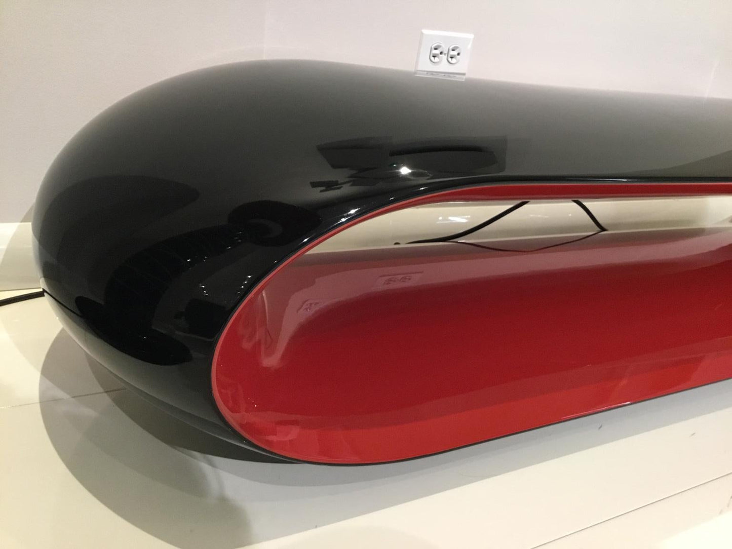 Black and red object on a white surface with a light gray wall in the background