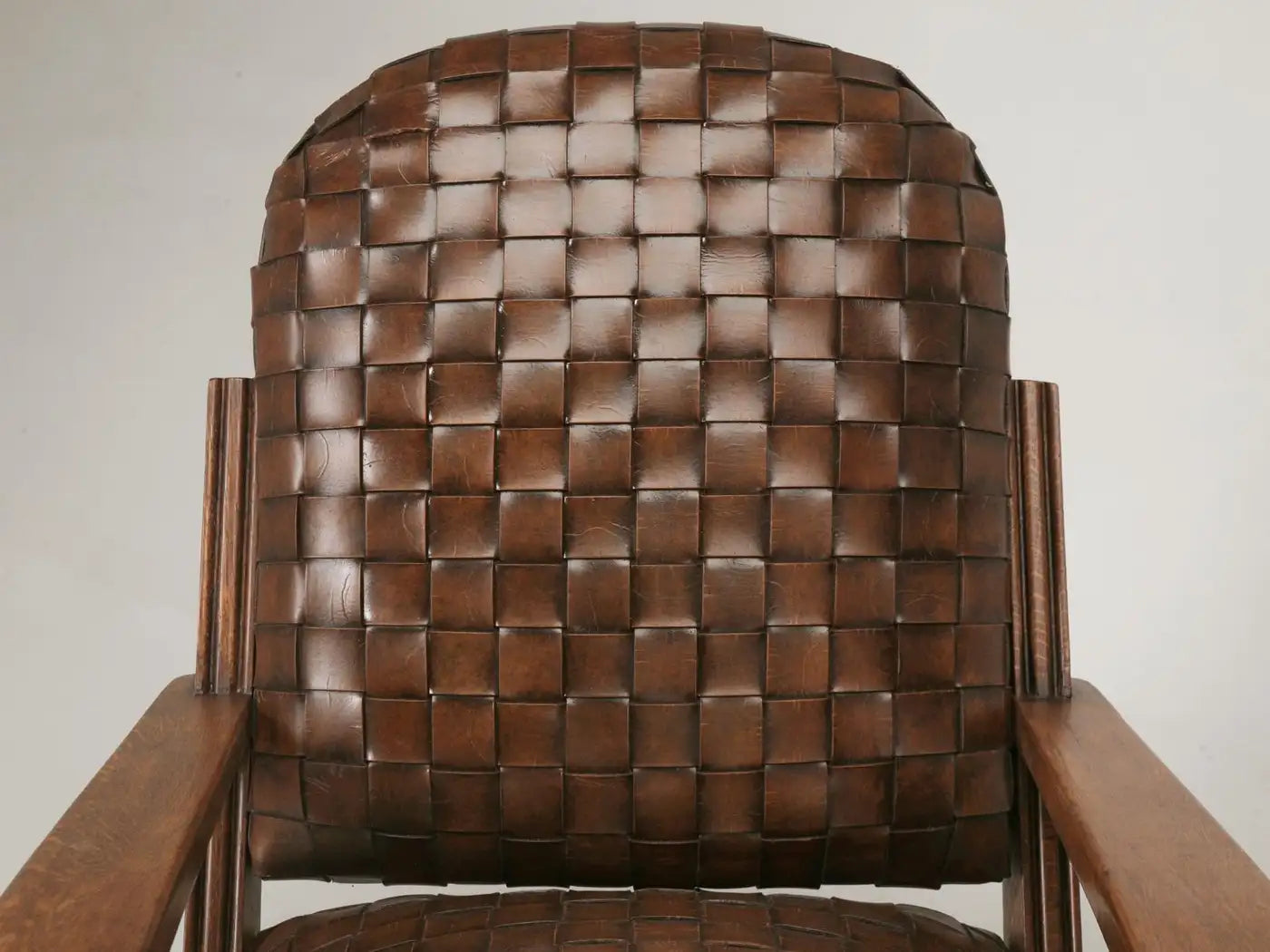 Brown woven chair with wooden frame against a white background