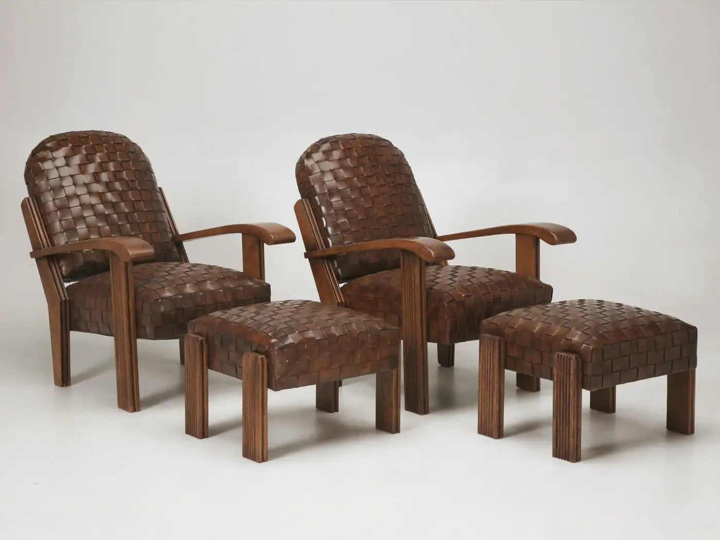 Two brown woven chairs with matching ottomans on a white background