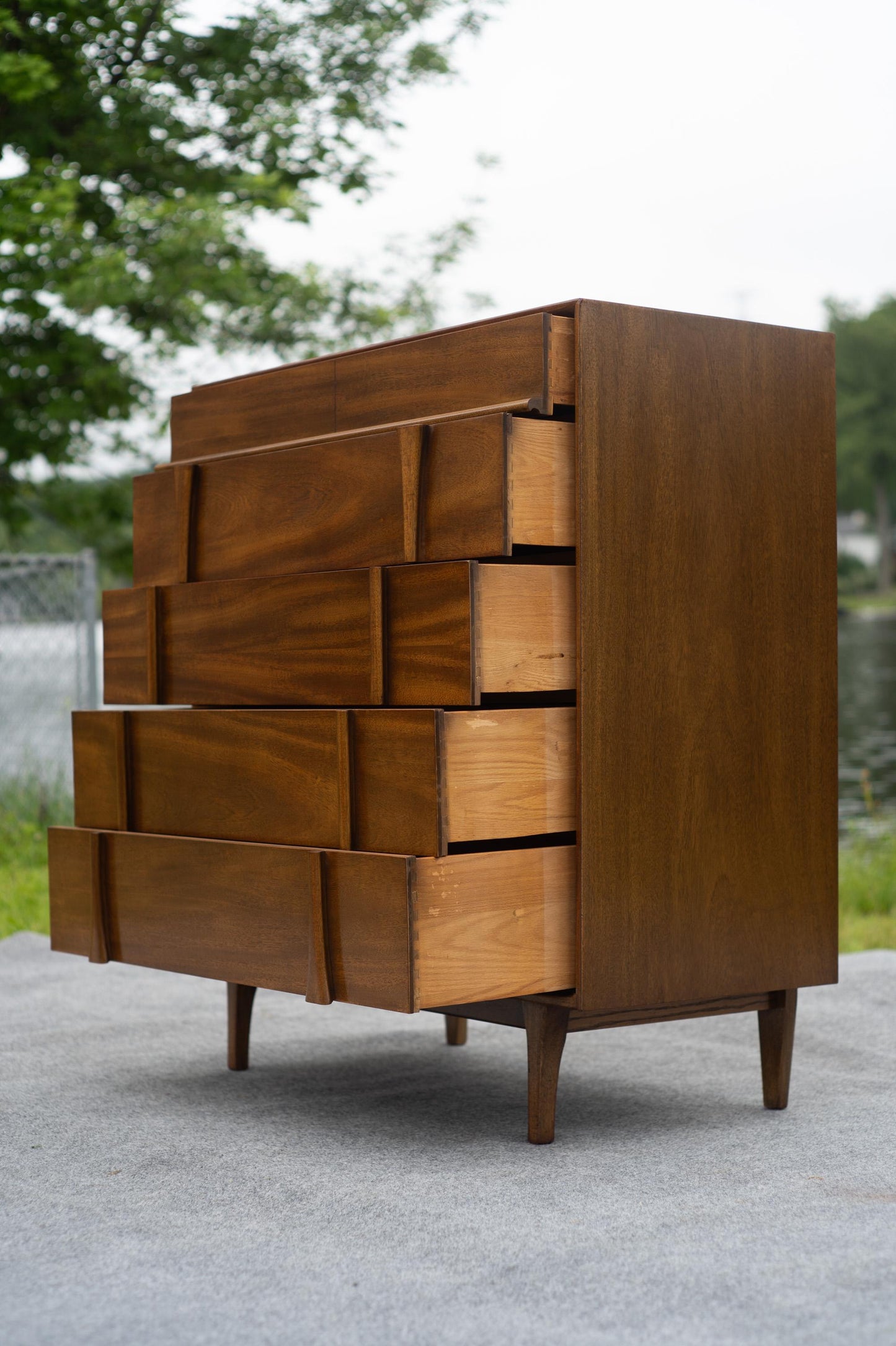 Wooden dresser with geometric design outdoors on a paved surface