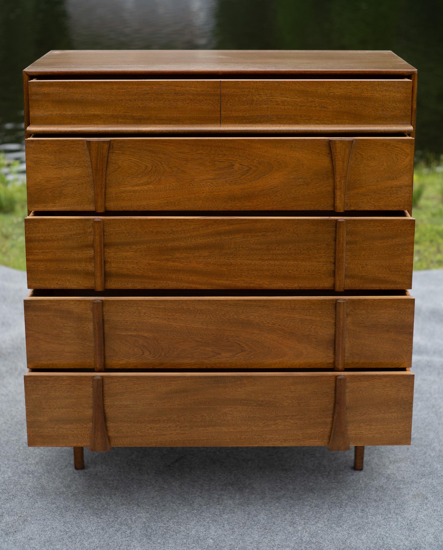 Wooden dresser with multiple drawers on a gray surface