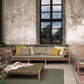 Outdoor seating area with a sofa, coffee table, and chairs against a textured wall with large windows.