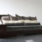 Gray sofa with dark wooden armrests against a white wall