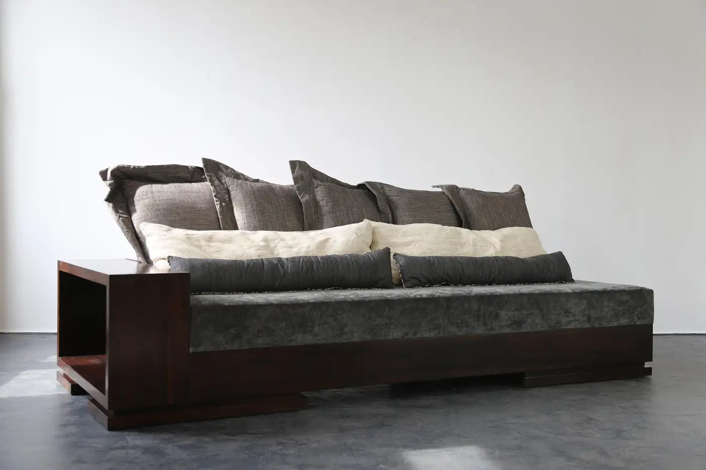 Gray sofa with dark wooden armrests against a white wall