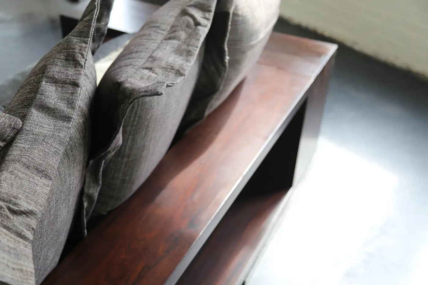 Gray cushions on a wooden bench with a blurred background