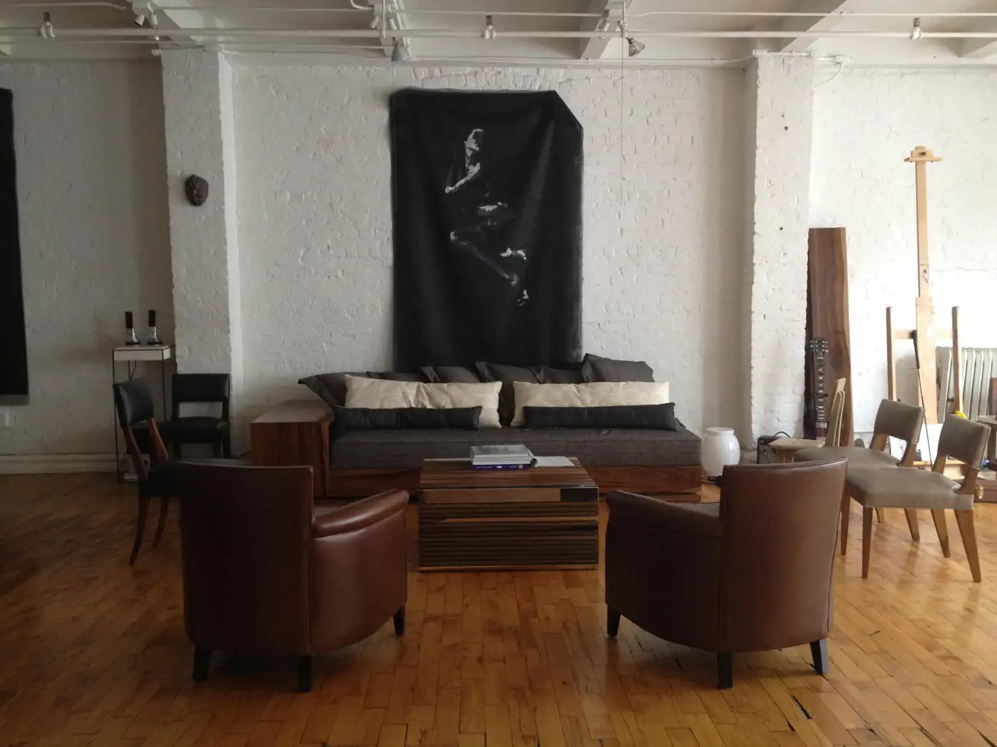 Living room with brown leather chairs, a gray sofa, and a black flag on the wall.