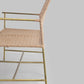 Chair with wicker seat and gold metal frame on a light gray background