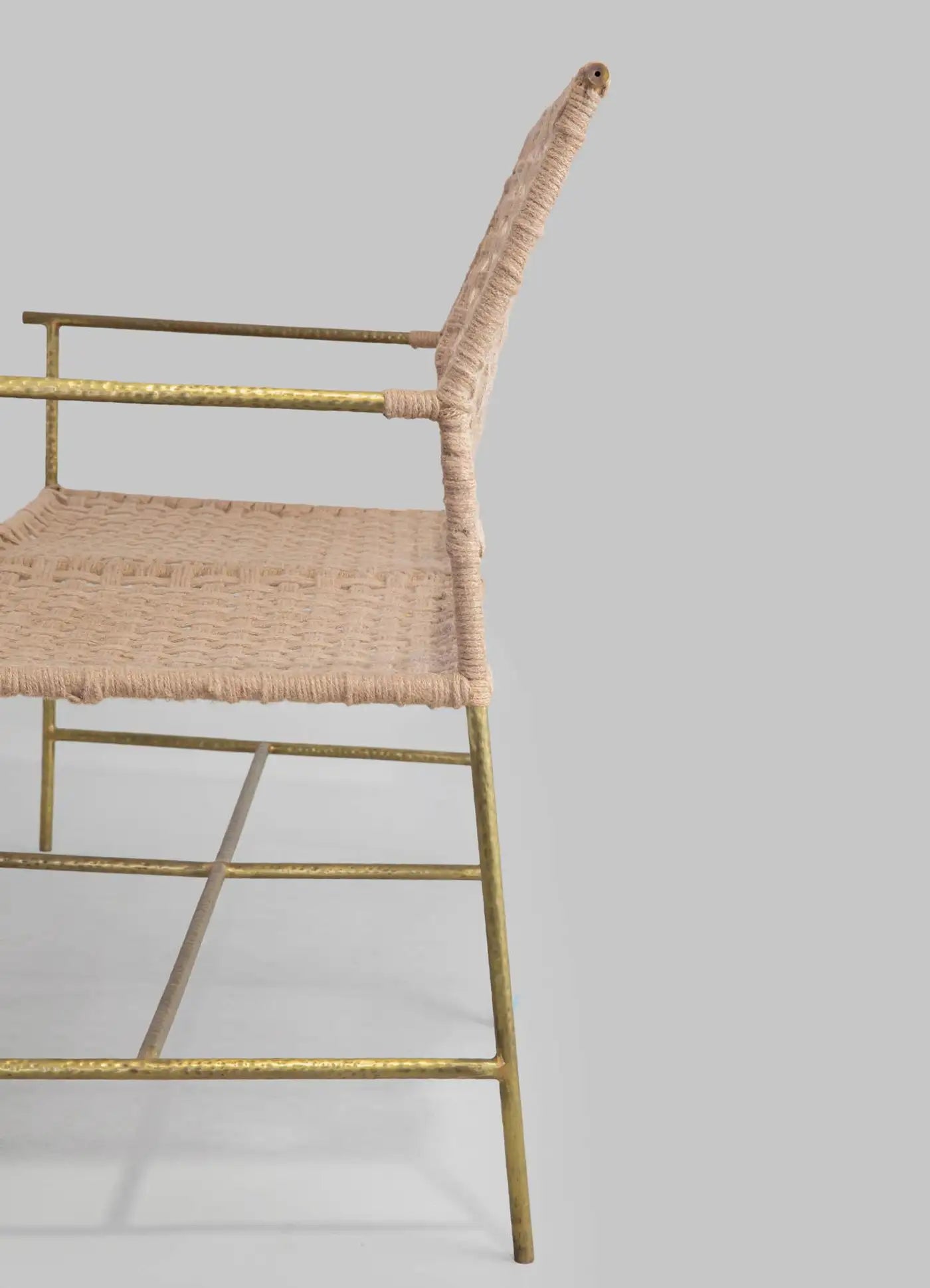 Chair with wicker seat and gold metal frame on a light gray background