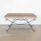 Bench with beige cushion and metal frame on a plain background