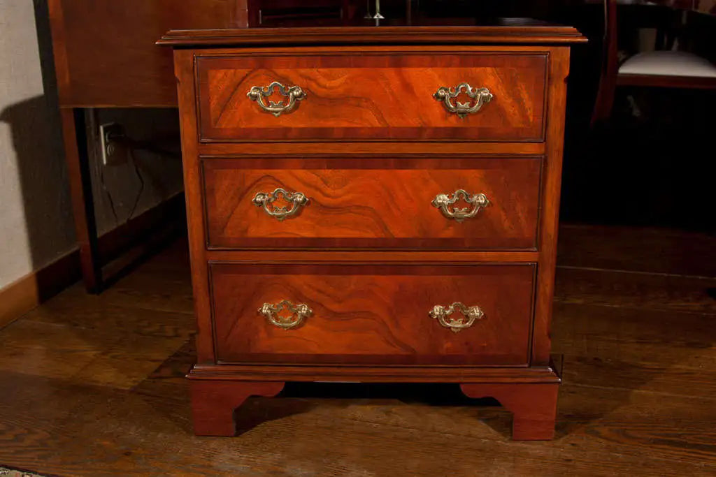 Wooden dresser with three drawers on a wooden floor.