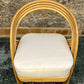 Wicker chair with a white cushion on a textured floor and wall background