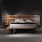 Wooden bed with a dark headboard in a dimly lit room