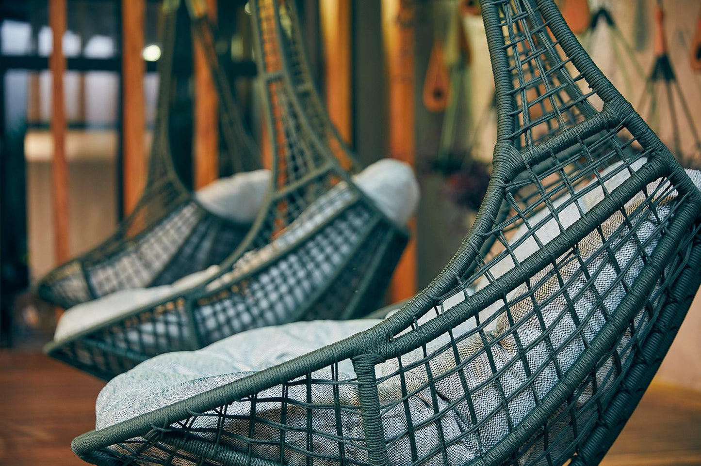 Hanging wicker chairs with cushions in a blurred indoor setting