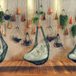 Hanging chairs with plants on a wall in a room with wooden flooring.