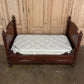 Wooden bed with a mattress against a wooden paneled wall.