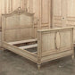 Vintage-style wooden bed with intricate carvings in a room with wooden paneling.