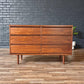 Wooden dresser against a gray brick wall on a wooden floor