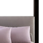 Gray upholstered headboard with pink pillows on a bed.