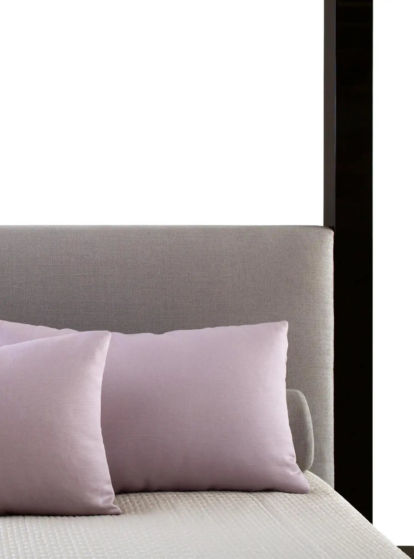 Gray upholstered headboard with pink pillows on a bed.