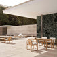 Outdoor patio area with wooden furniture and a pool in the background