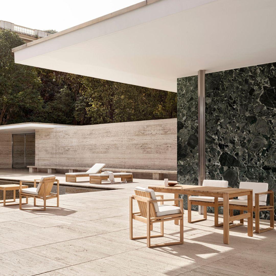 Outdoor patio area with wooden furniture and a pool in the background