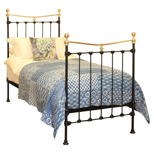 Bed with black metal frame and gold accents, covered with a blue patterned comforter on a white background.