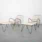 Two modern chairs with ottomans on a gray floor against a white wall