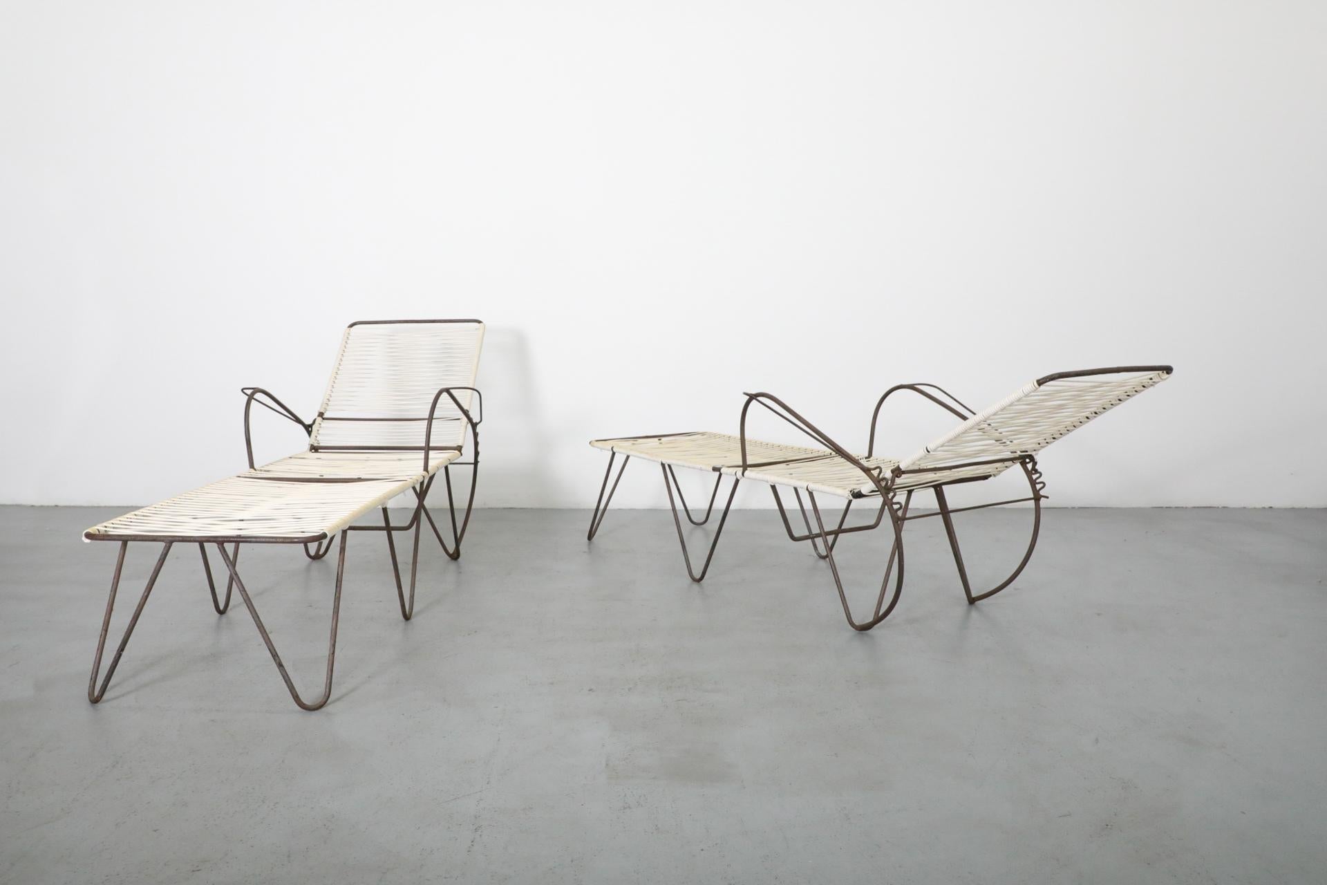 Two modern lounge chairs with metal frames and woven seats on a gray floor.