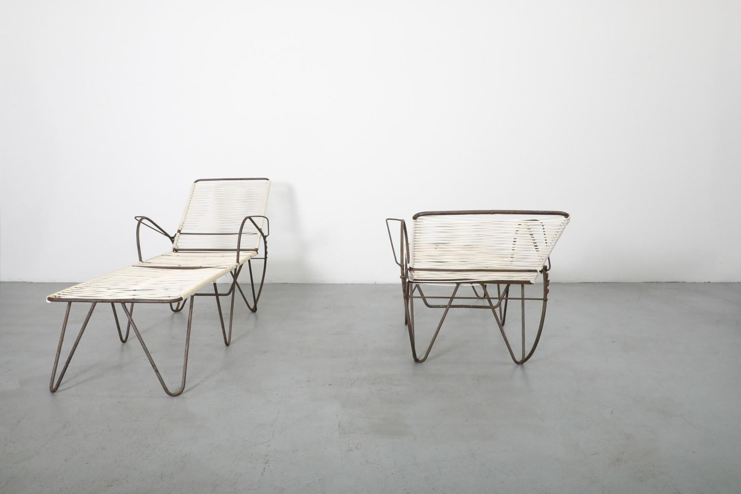 Modern outdoor furniture set with lounge chairs and table on a gray floor.