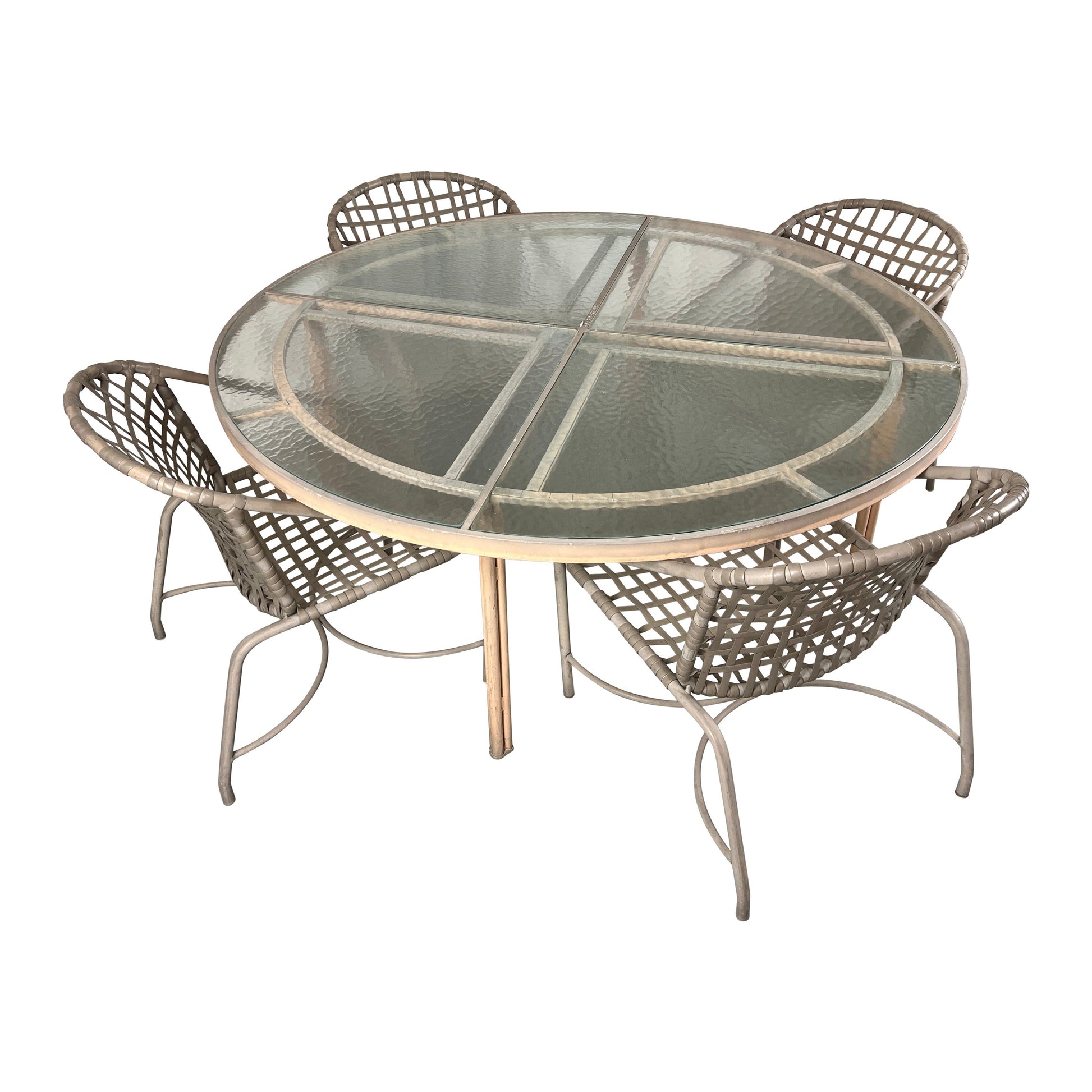 Round glass-top dining table with four wicker chairs on a white background