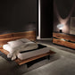Modern bedroom with wooden bed and dresser in a dimly lit room.