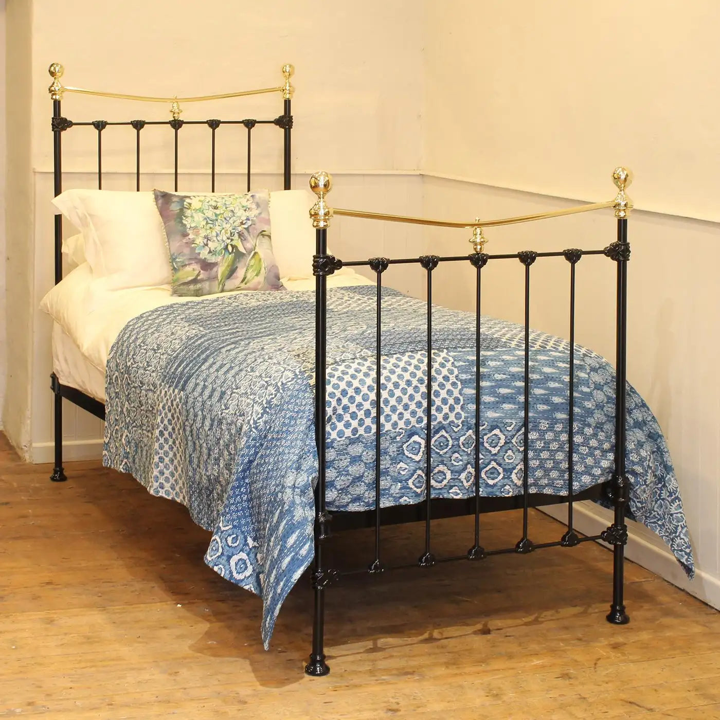 Bed with black metal frame, gold accents, and blue patterned bedding in a room.