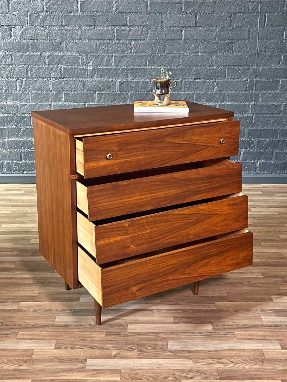 Wooden dresser with four drawers against a brick wall.