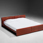 Red bed frame with white mattress on a gray background