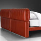 Red leather bed frame with white mattress on a gray background