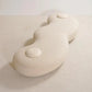 White ceramic vase with a smooth, organic shape on a light beige background
