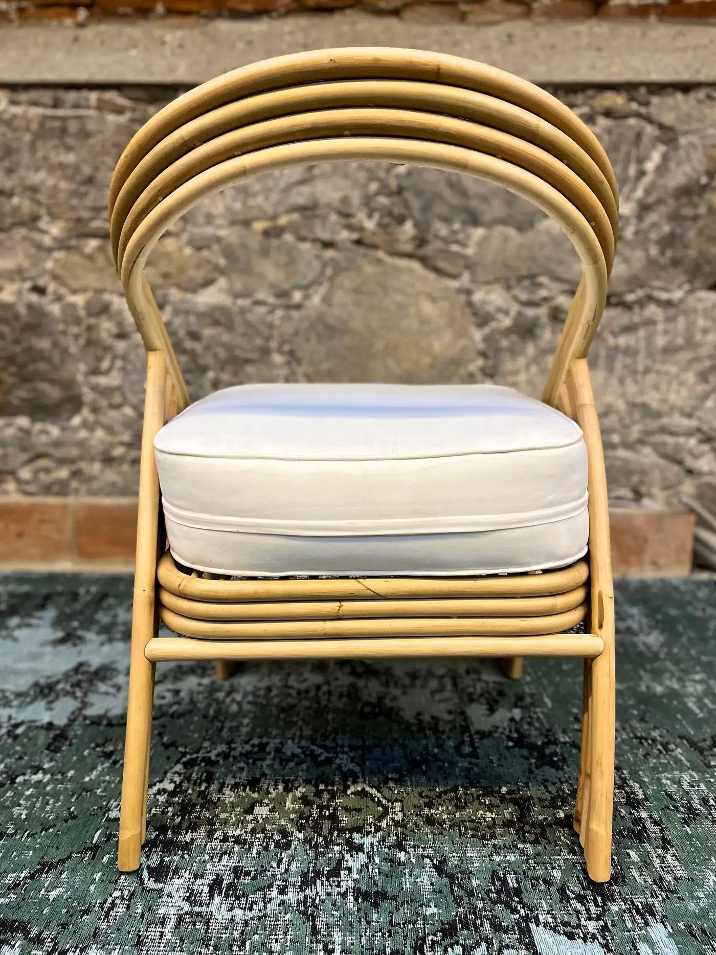 Stack of rattan chairs with a cushion on a textured surface