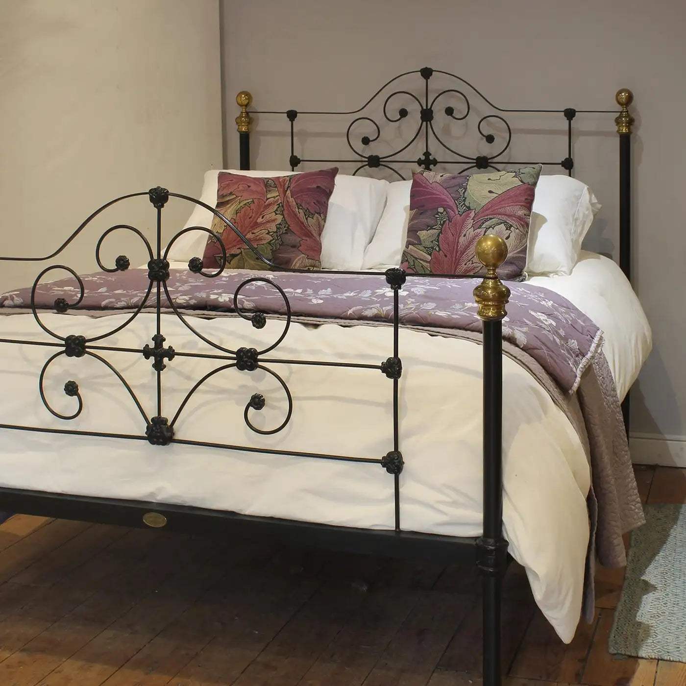 Decorative bed with ornate metal headboard and bedding in a room.