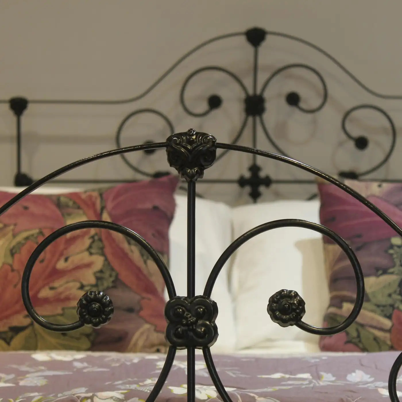 Decorative metal headboard with floral patterns on a bed.