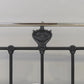 Decorative iron bed rail with intricate design on a plain background