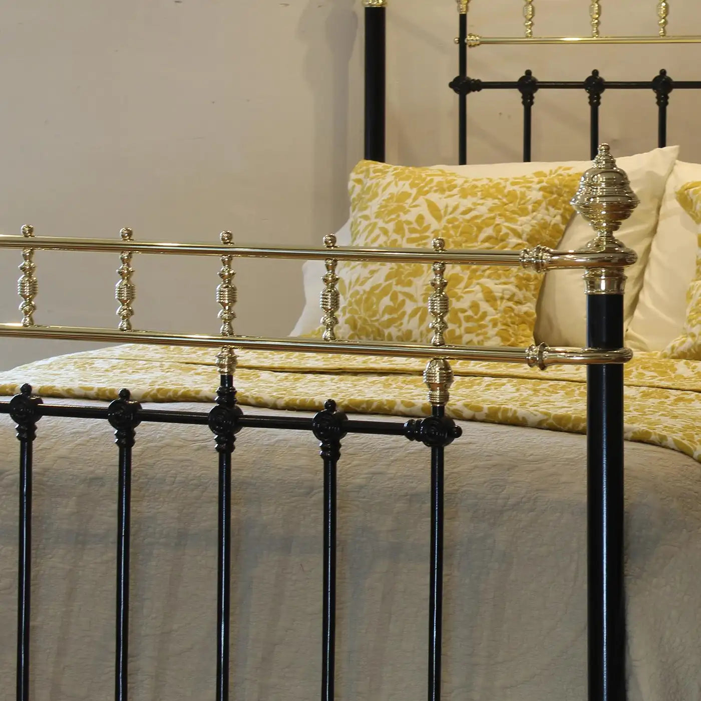 Decorative bed with gold and black metal headboard and yellow patterned pillows.